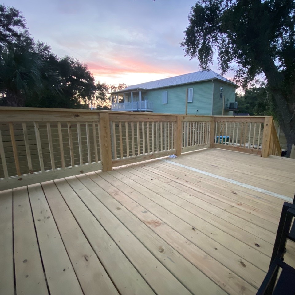 A wooden deck with a fence and a house in the background