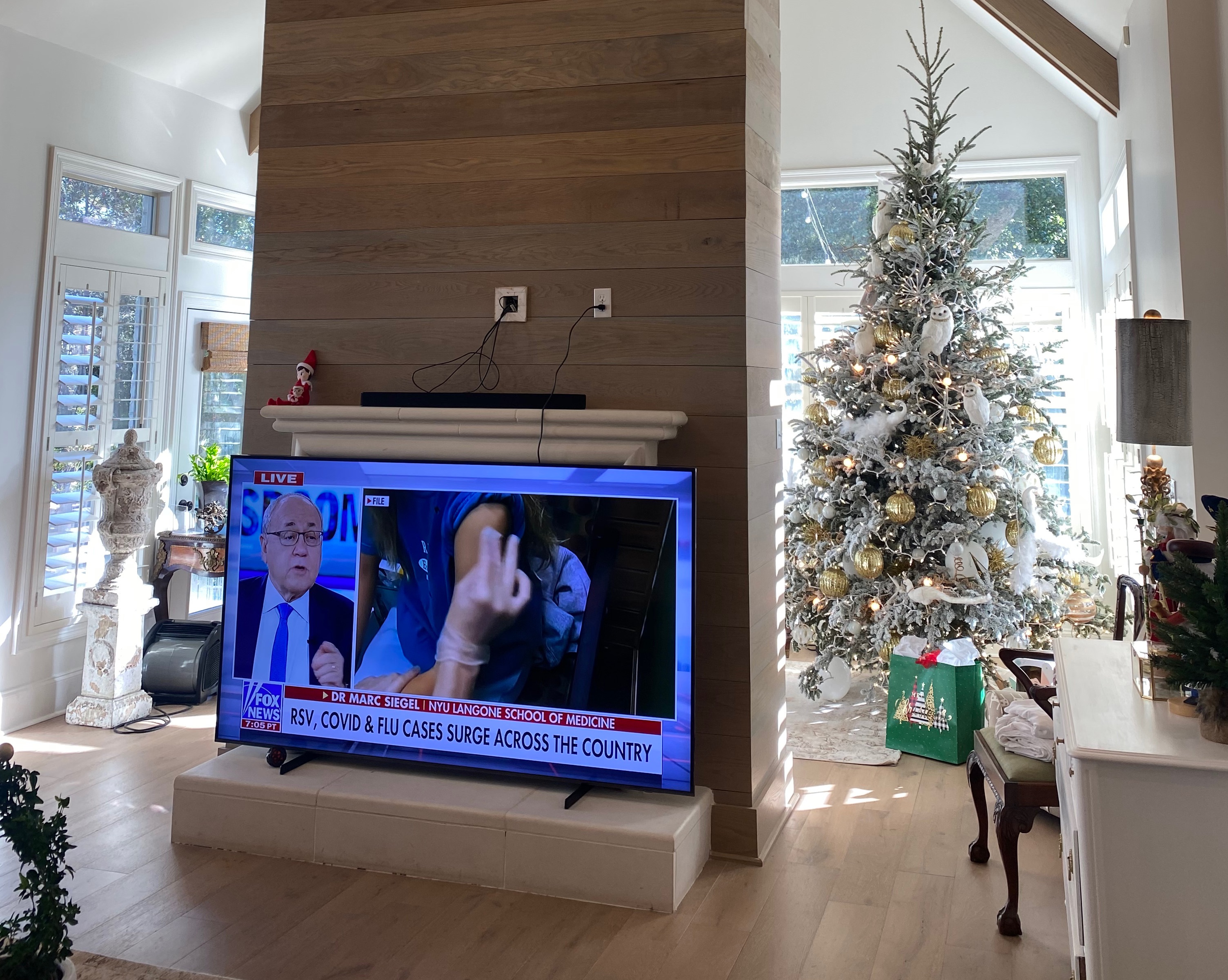 A television sitting in a living room next to a christmas tree